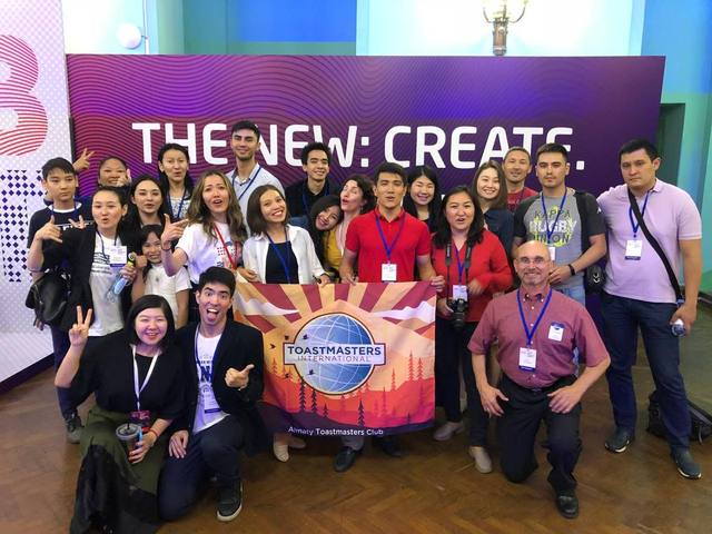 Almaty Toastmasters Club members with the club banner at an event