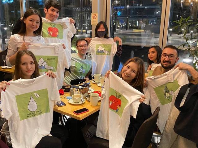 A group in a café holding up printed T-shirts