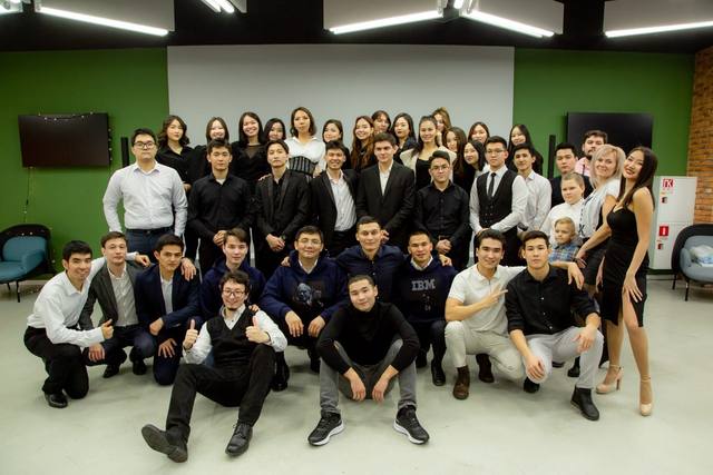 A large group photo at a formal event, in front of a green wall